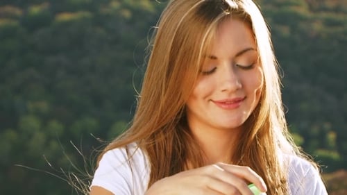 Smiling Woman Blowing Bubbles in Natural Setting