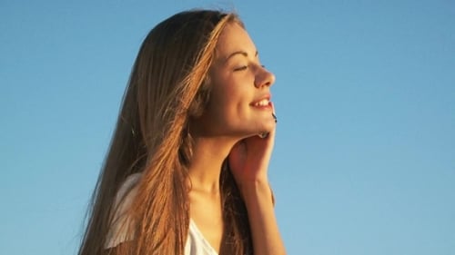 Smiling Woman Talking on Phone Against Blue Sky