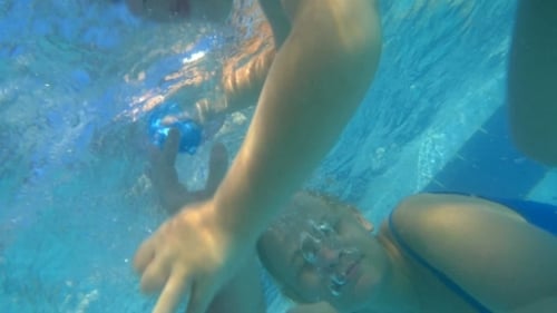 Child Swims Underwater with Family in Tropical Pool