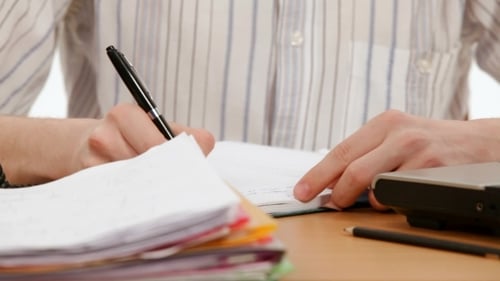 Man Writing in Notebook on Wooden Desk