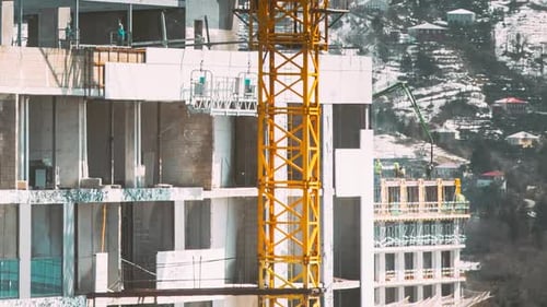 Los trabajadores trabajan en una cuna de construcción sobre andamios durante la construcción de un edificio de gran altura