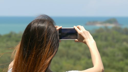 Woman Taking Picture of Ocean View With Phone