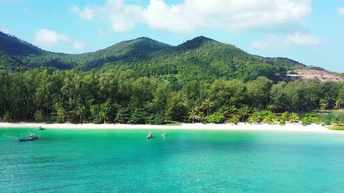 Calm turquoise lagoon reflecting green vegetation of tropical island shoreline with palm trees and w