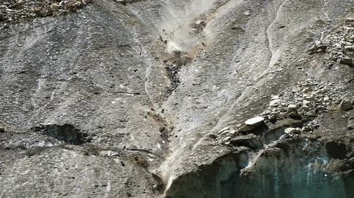 Zeitlupen-Steinschlag in den Bergen Nahaufnahme. Steinklumpen fallen vom schmelzenden Gletscher
herab