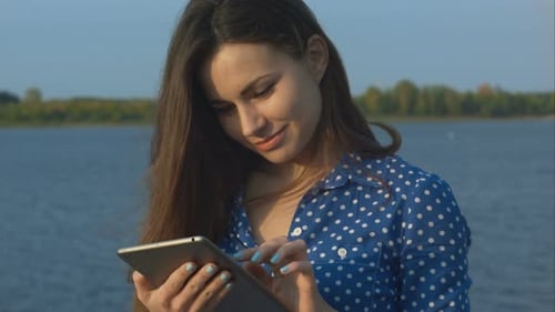 Young Woman Using Tablet By Lake