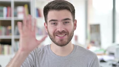 Cheerful Young Adult Waving Hand Indoors