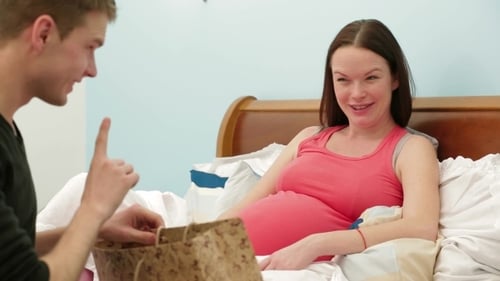 Expectant Couple Receiving Adorable Baby Gifts in Bed