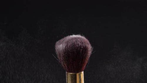 Dos Pinceles de maquillaje con polvo sobre un fondo oscuro