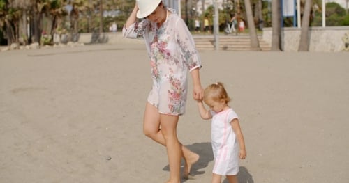Mother With Her Daughter Walking At The Beach
