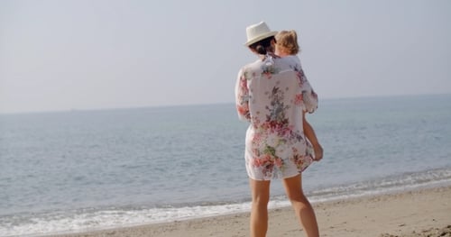 Woman Standing On Beach Holding Small Child
