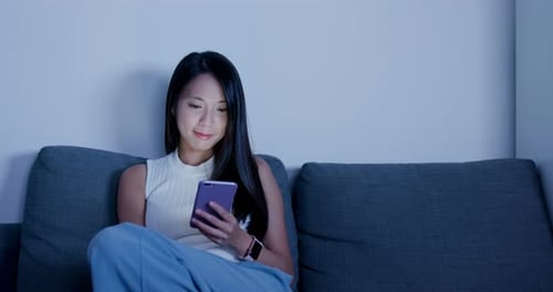 Woman Using Phone on Couch at Night