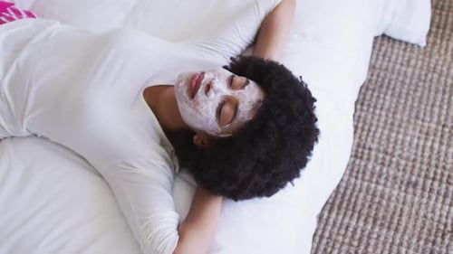 Woman with Facial Mask Lying on Bed Smiling