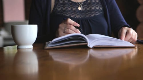 Woman Journaling Indoors at a Table with Coffee
