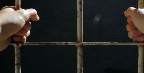 Close Up Hands Gripping Prison Bars