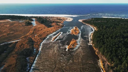 High Angle Melting Snow and Ice at River Joining Sea in Spring Aerial