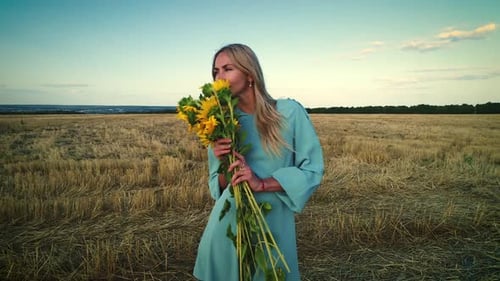 Girl Sniffing Flowers. Young Sunflowers