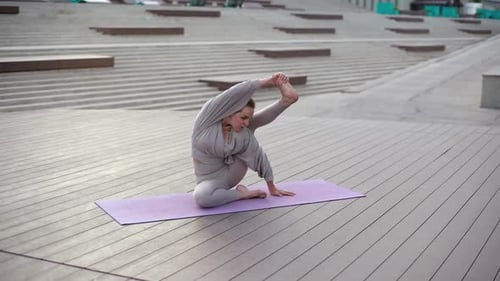 Front View of Professional Yoga Trainer Practicing Advanced Yoga Poses Sitting on Yoga Mat Outdoors