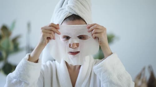 Portrait of a Young Domestic Woman Apply Tissue Face Mask for Skin Care Un the Bathroom