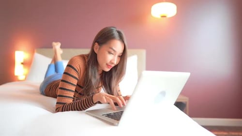 Woman Lies On Bed Using Laptop