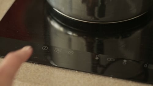 Finger Turns On Induction Cooktop in Modern Kitchen