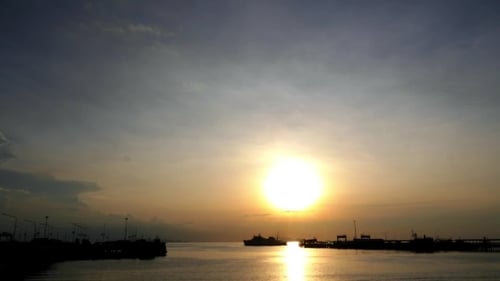 Puesta de sol dorada sobre barcos de vela en el muelle o