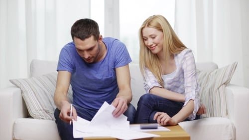 Couple Reviewing Documents Together on Sofa at Home