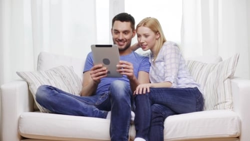 Happy Couple Looking at Tablet Together on Couch