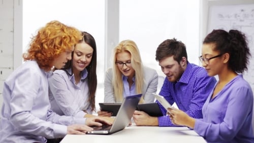 Equipe sorridente com computadores portáteis e de mesa