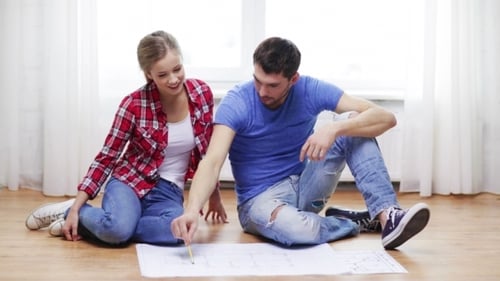Happy Couple Discussing Blueprint At Home