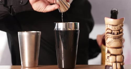 Bartender Pouring Cocktail Into A Bartending Tumble With A Cocktail Shaker On The Bar Counter - clos