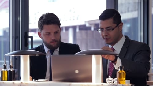 Two Businessmen Collaborate on Laptop in Modern Office