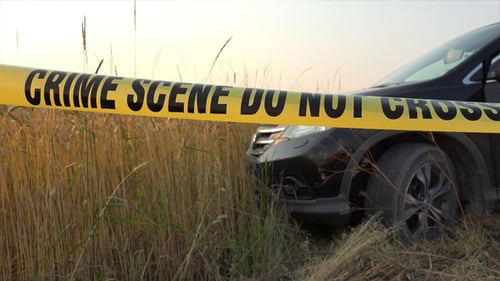 Crime Scene Tape at Vehicle in Field