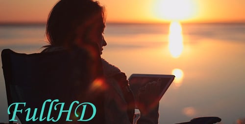 Woman Working on Tablet at Sunset on Beach