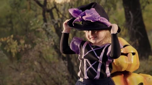 Little Girl in Witch Costume Posing Near Pumpkin