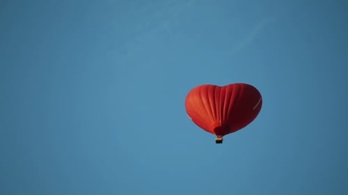 Red Heart Hot Air Balloon Flying in Blue Sky