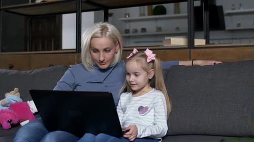 Woman and Child Using Laptop Together on Couch