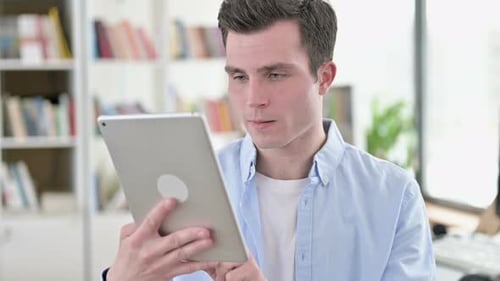 Young Man Reacts with Joy to Tablet