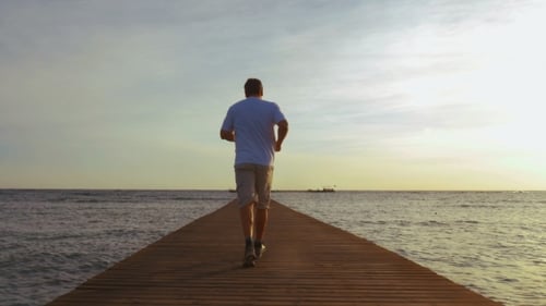 Man Jogging On The Pier At Sunset