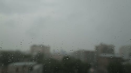 Rain Drops on Window with Blurred Cityscape