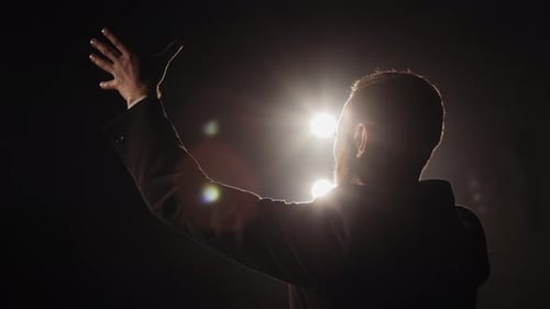 Passionate Man Giving Speech on Dark Stage