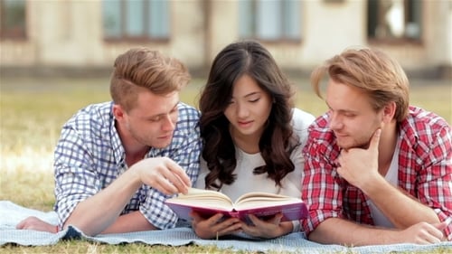 Three Students Relaxing On Meadow