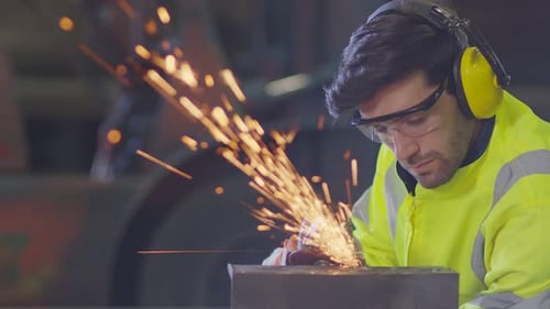 Focused Worker Grinding Metal Showering Sparks