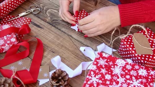 Hands Wrapping Christmas Present on Wooden Table