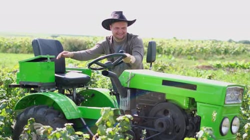Man Drives Tractor Through Field on Sunny Day