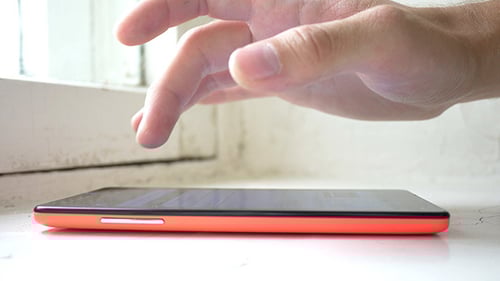 Hand Using Smart Phone on Window Sill