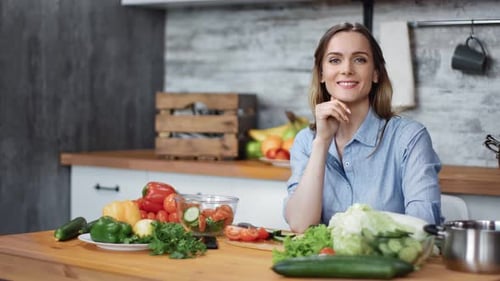 Woman Smiling with Salad Ingredients in Kitchen