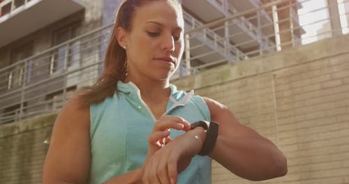 Athletic Woman Checking Smartwatch in Urban Setting