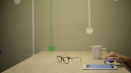 Hand Using Tablet on Bright Desk with Accessories