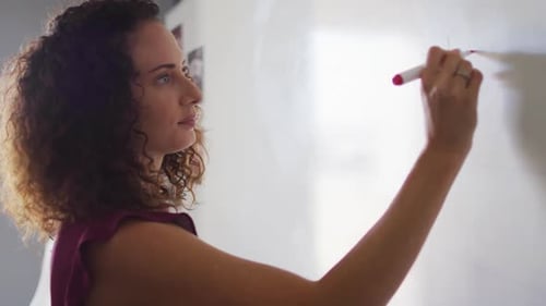 Woman Writes on White Board in Workplace