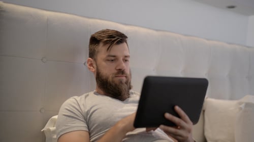 Man in Bed Using Tablet Device